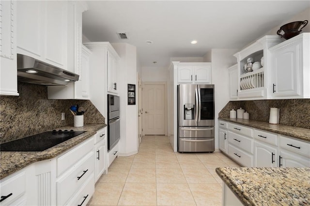 kitchen featuring white cabinetry, stainless steel appliances, tasteful backsplash, dark stone counters, and light tile patterned floors