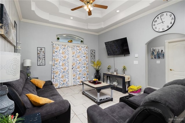 living room featuring a raised ceiling, ceiling fan, and ornamental molding