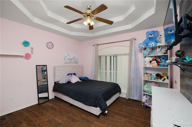 bedroom with a raised ceiling, ceiling fan, and dark hardwood / wood-style floors