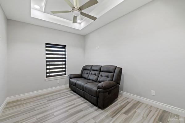 sitting room featuring a tray ceiling, ceiling fan, and light wood-type flooring