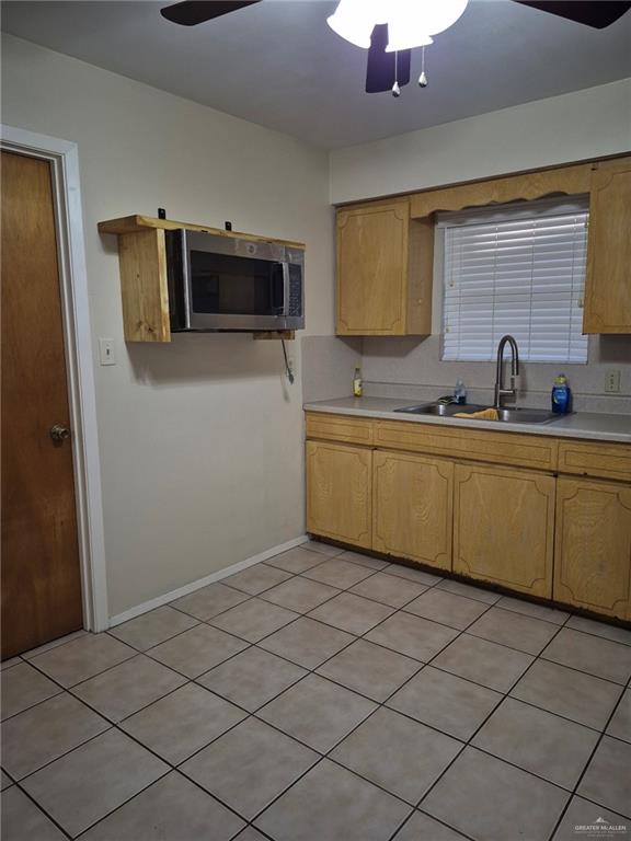 kitchen featuring light tile patterned floors, ceiling fan, and sink