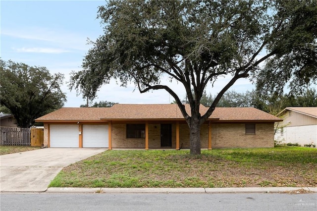 ranch-style home featuring brick siding, concrete driveway, an attached garage, fence, and a front yard