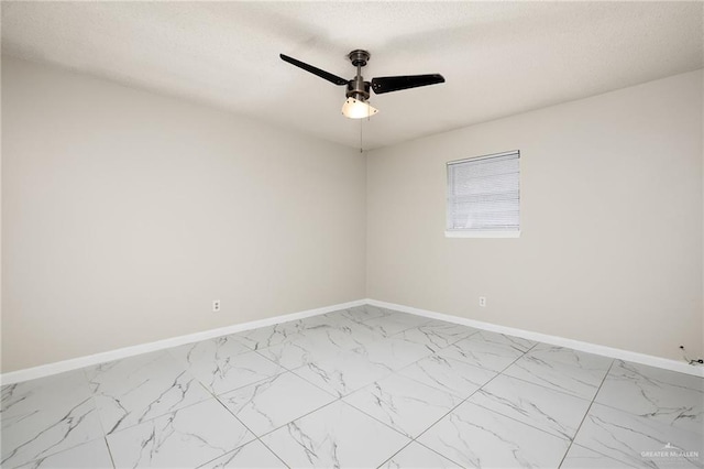 spare room featuring marble finish floor, baseboards, and a ceiling fan