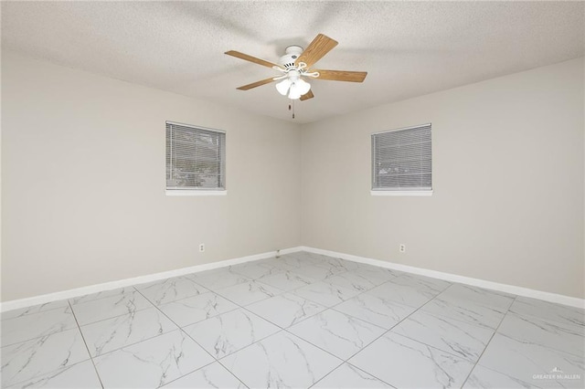 unfurnished room with a ceiling fan, marble finish floor, a textured ceiling, and baseboards