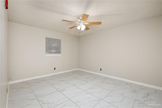 unfurnished room with ceiling fan, marble finish floor, a textured ceiling, and baseboards