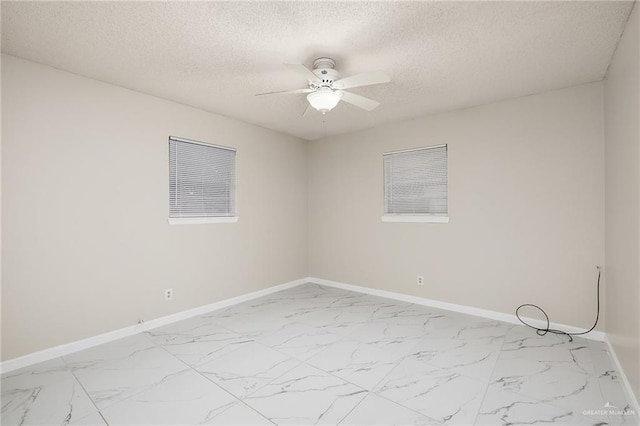 spare room featuring marble finish floor, ceiling fan, and baseboards