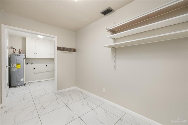 clothes washing area featuring water heater, marble finish floor, visible vents, and baseboards