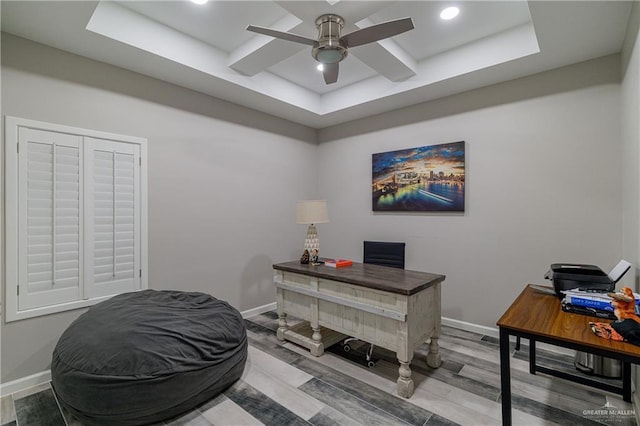 office area with hardwood / wood-style flooring, a raised ceiling, and ceiling fan