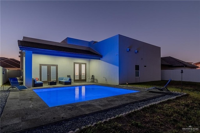 back house at dusk with french doors and a patio