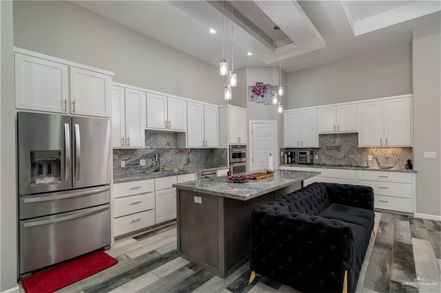 kitchen with white cabinetry, a center island, a high ceiling, a kitchen bar, and appliances with stainless steel finishes