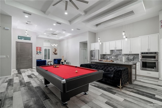 playroom with ceiling fan, a towering ceiling, pool table, beamed ceiling, and light hardwood / wood-style floors