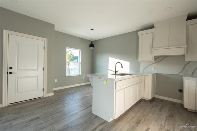 kitchen with pendant lighting, sink, white cabinetry, tasteful backsplash, and kitchen peninsula