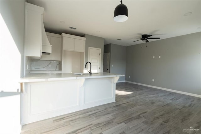 kitchen featuring sink, hanging light fixtures, white cabinets, ceiling fan, and backsplash