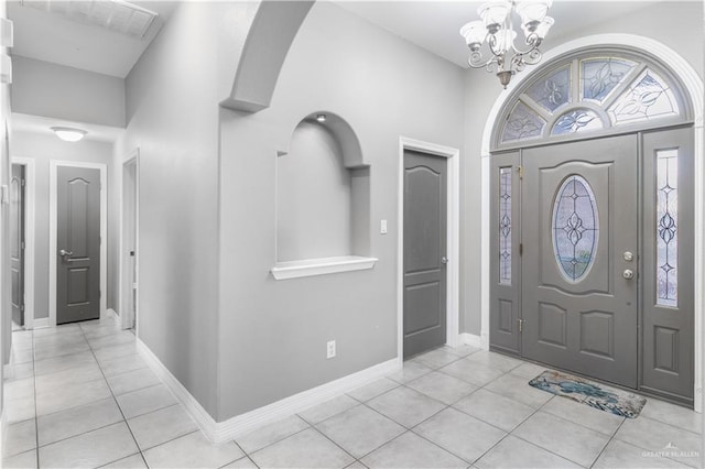 foyer entrance with baseboards, light tile patterned flooring, and an inviting chandelier