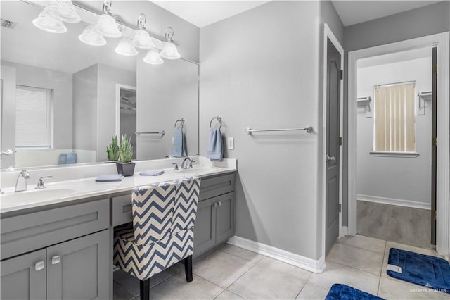 bathroom featuring double vanity, baseboards, a sink, and tile patterned floors