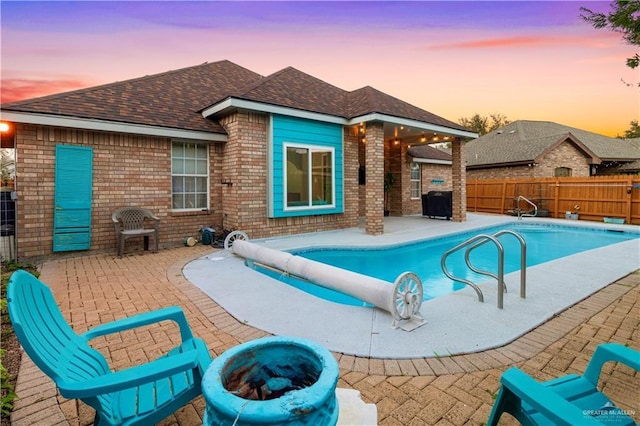 pool at dusk featuring fence, a fire pit, a fenced in pool, and a patio