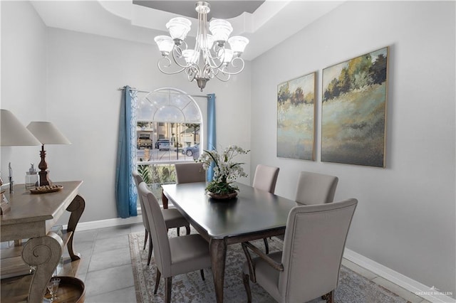 dining space with a notable chandelier, light tile patterned floors, a raised ceiling, and baseboards