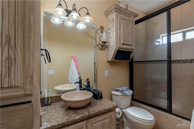 full bathroom featuring a notable chandelier, vanity, toilet, and bath / shower combo with glass door