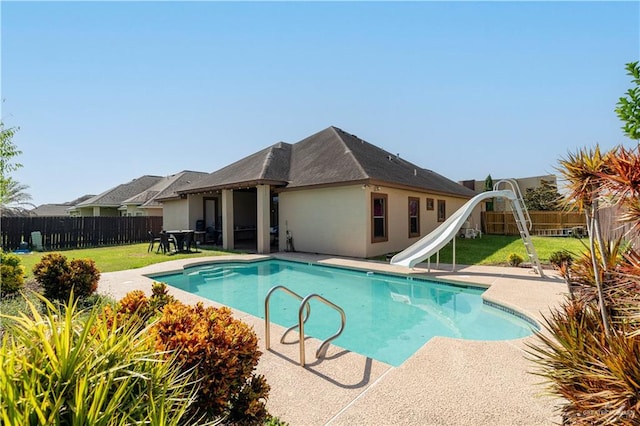 view of pool featuring a yard, a water slide, and a patio