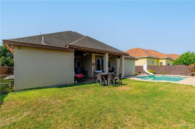 back of house featuring a fenced in pool and a lawn