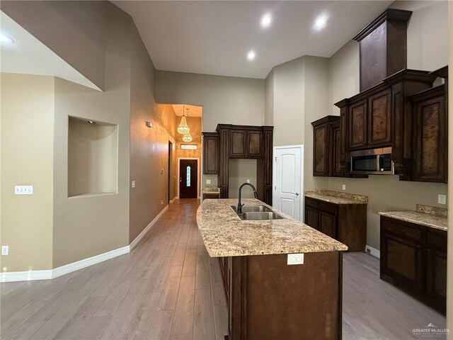 2315 N Ruby Dr, Edinburg, TX 78541 - kitchen featuring a sink, a center island with sink, a towering ceiling, dark brown cabinets, and baseboards