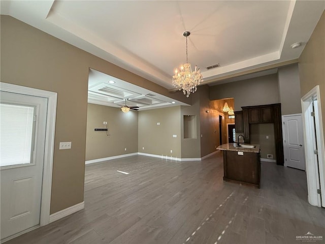 2315 N Ruby Dr, Edinburg, TX 78541 - unfurnished living room featuring a chandelier, a sink, a tray ceiling, baseboards, and wood finished floors