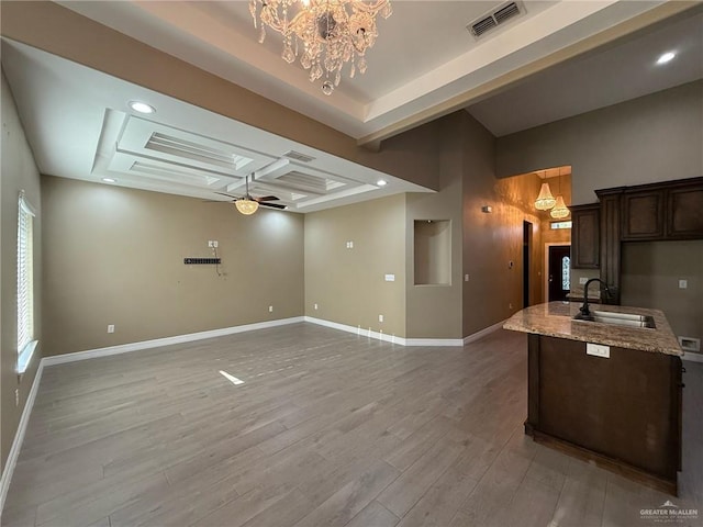 2315 N Ruby Dr, Edinburg, TX 78541 - kitchen featuring a sink, a tray ceiling, light wood finished floors, dark brown cabinets, and light stone counters