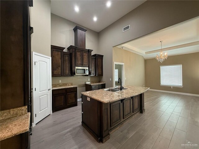 2315 N Ruby Dr, Edinburg, TX 78541 - kitchen with stainless steel microwave, a sink, a chandelier, light wood finished floors, and a kitchen island with sink