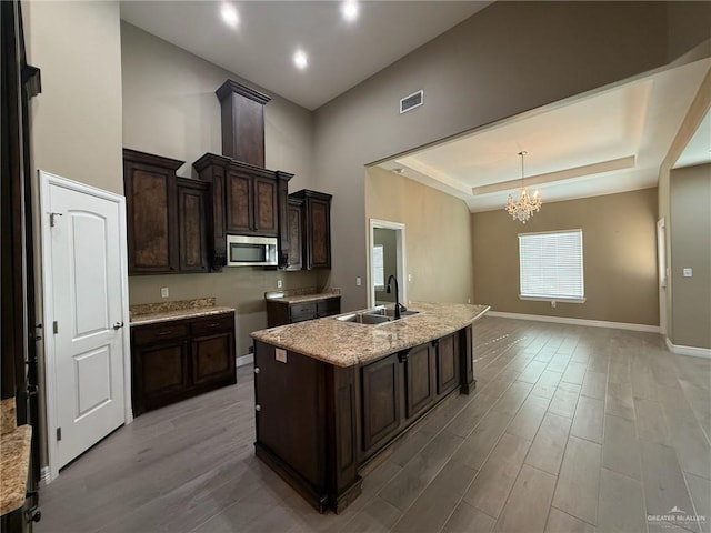 2315 N Ruby Dr, Edinburg, TX 78541 - kitchen with stainless steel microwave, a sink, a chandelier, baseboards, and light wood-style flooring