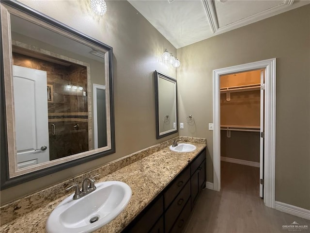 2315 N Ruby Dr, Edinburg, TX 78541 - bathroom featuring a shower stall, double vanity, a spacious closet, baseboards, and wood finished floors