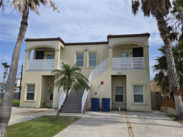 115 E Atol St Unit 3, South Padre Island, TX 78597 - view of front of home featuring stairway, stucco siding, a balcony, concrete driveway, and a tiled roof