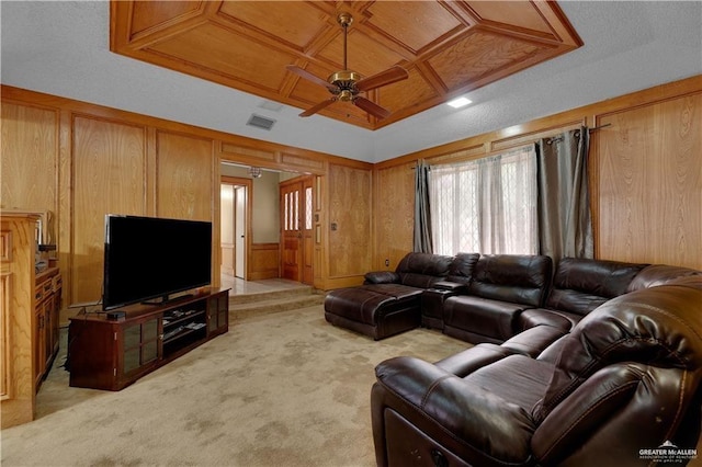 living room featuring a ceiling fan, light colored carpet, coffered ceiling, and wooden walls