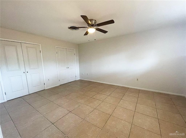 807 Walnut St, Mcallen, TX 78501 - unfurnished bedroom featuring two closets, light tile patterned flooring, baseboards, and ceiling fan