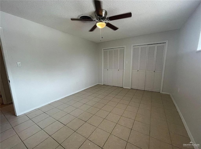 807 Walnut St, Mcallen, TX 78501 - unfurnished bedroom featuring multiple closets, a textured ceiling, light tile patterned flooring, ceiling fan, and baseboards