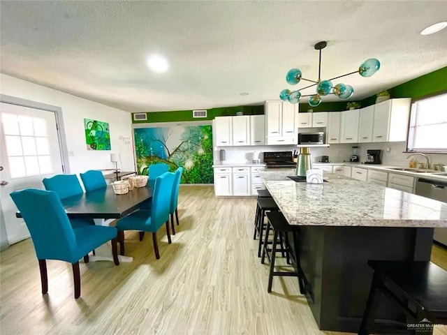 807 Walnut St, Mcallen, TX 78501 - kitchen featuring stainless steel appliances, a sink, a textured ceiling, a center island, and a kitchen breakfast bar
