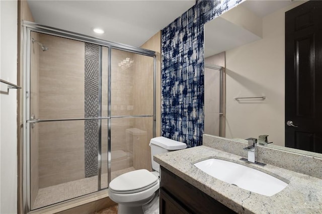 bathroom with a shower with door, vanity, and toilet