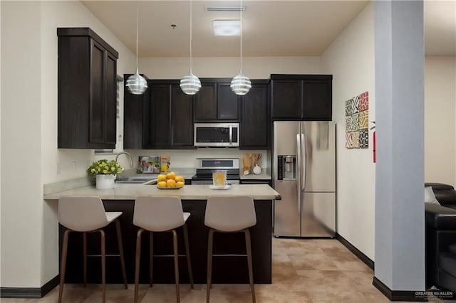 kitchen with sink, a breakfast bar area, hanging light fixtures, stainless steel appliances, and kitchen peninsula