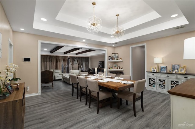 dining area with dark hardwood / wood-style flooring, a chandelier, and a tray ceiling