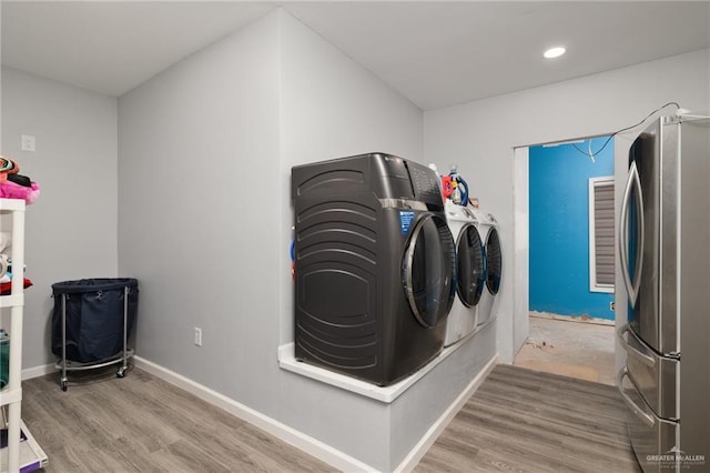 laundry room featuring wood-type flooring and separate washer and dryer