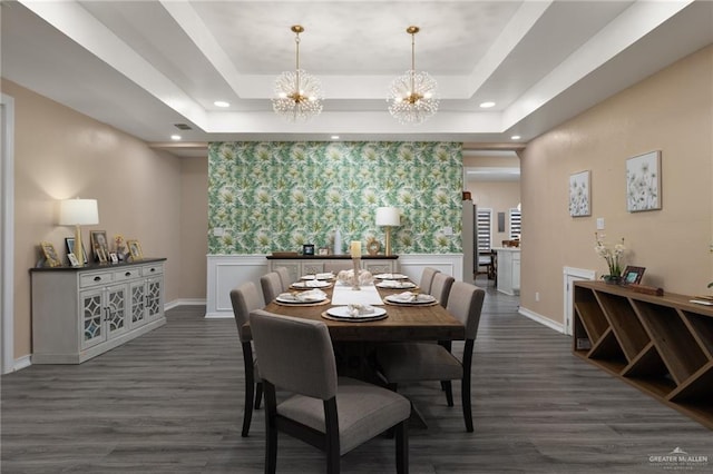 dining area with dark wood-type flooring, a notable chandelier, and a tray ceiling