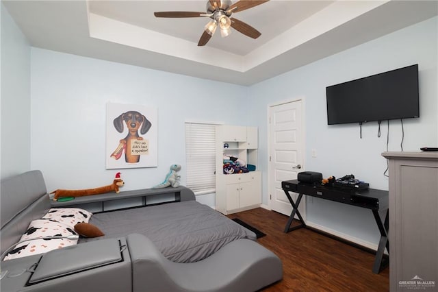 bedroom featuring ceiling fan, dark hardwood / wood-style floors, and a raised ceiling