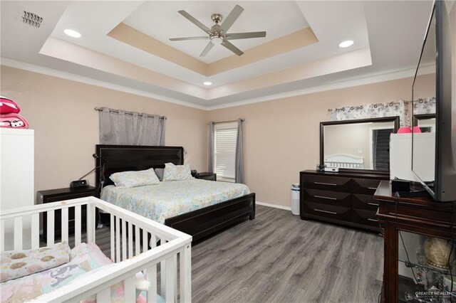 bedroom with hardwood / wood-style flooring and a raised ceiling