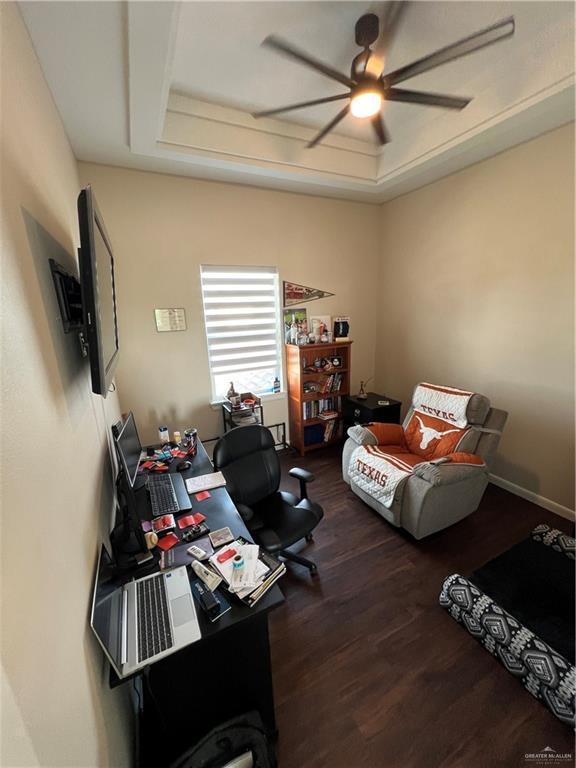 office with ceiling fan, dark hardwood / wood-style floors, and a tray ceiling