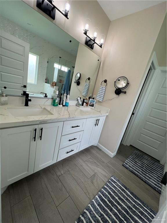 bathroom featuring a shower with door and vanity