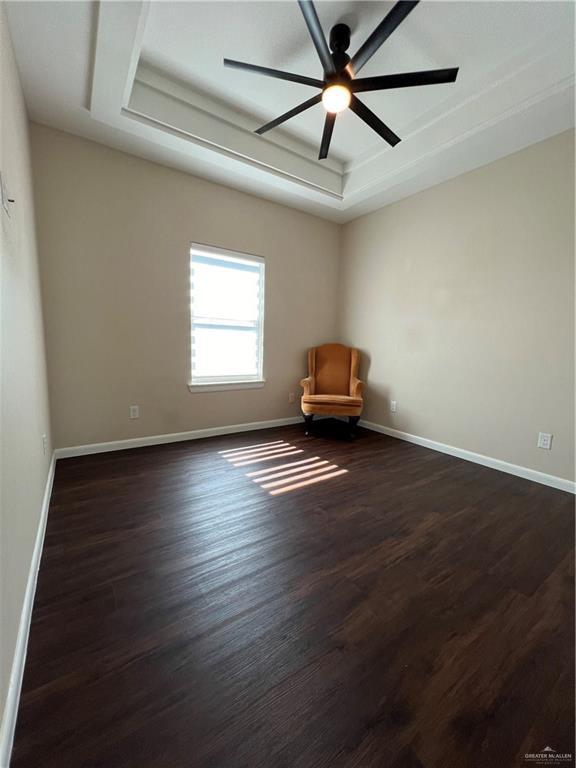 unfurnished room featuring ceiling fan, a raised ceiling, and dark hardwood / wood-style floors