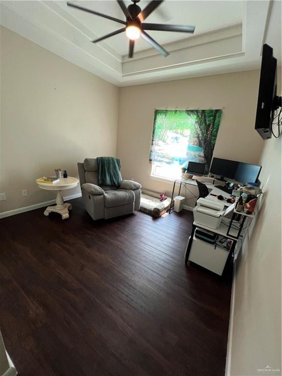 living room featuring dark wood-type flooring, ceiling fan, and a tray ceiling