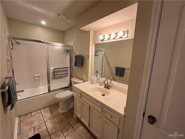 full bathroom with tile patterned flooring, bath / shower combo with glass door, a textured ceiling, toilet, and vanity