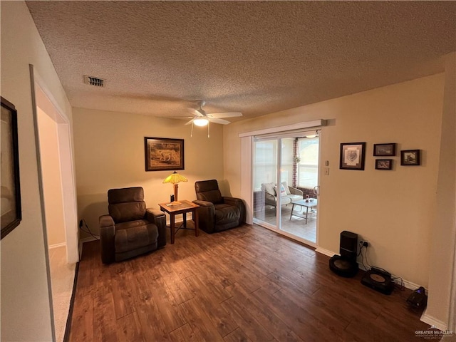 sitting room with ceiling fan, hardwood / wood-style floors, and a textured ceiling