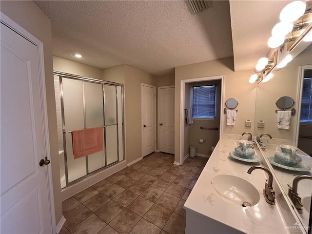 bathroom with a textured ceiling, vanity, an enclosed shower, and toilet