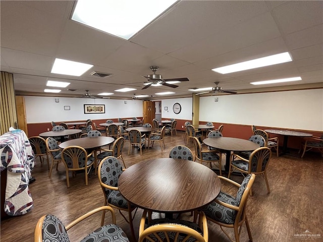 dining space with dark hardwood / wood-style floors, ceiling fan, and a drop ceiling